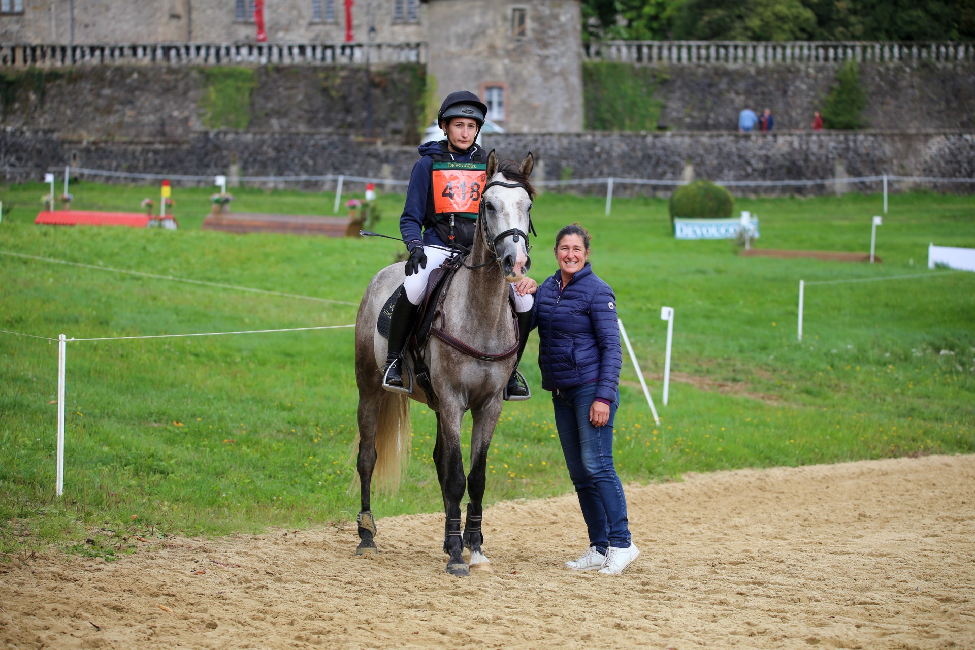 Cavalière et sa monitrice en concours devant un château